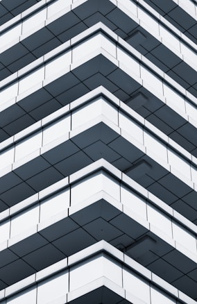 A modern building with a series of balconies arranged in a geometric, repeating pattern. The design creates a visual illusion of overlapping and intersecting lines, enhancing its architectural appeal.