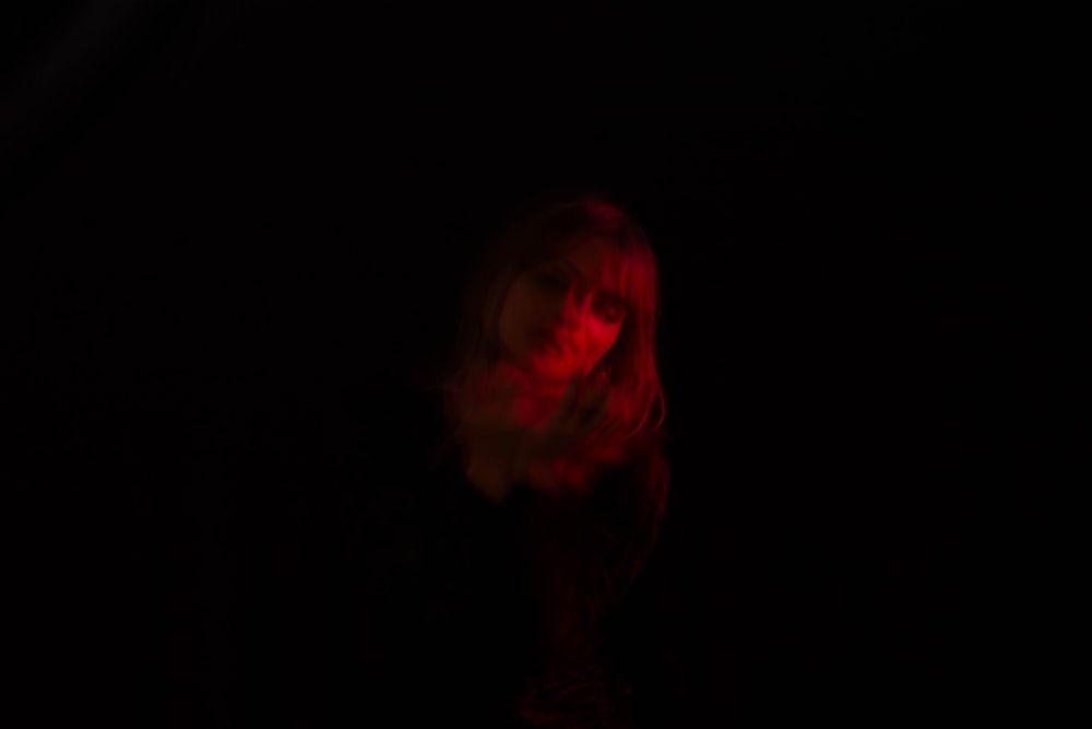 a woman standing in the dark with a red light on her face