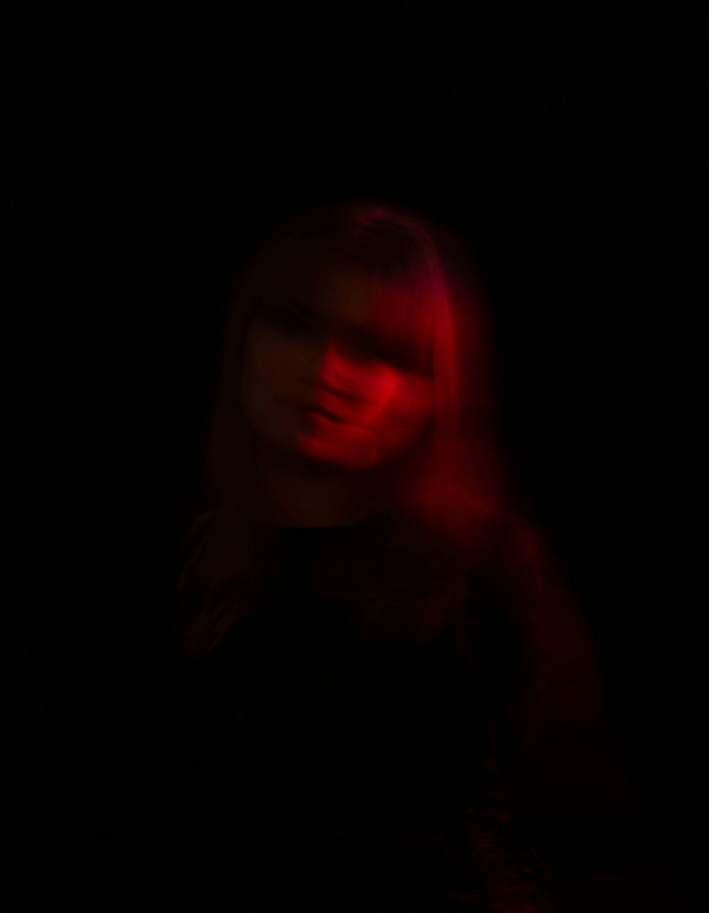 a woman standing in the dark with a red light on her face