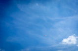 A wide shot of a clear blue sky with a small airplane soaring high, symbolizing dreams of flight.