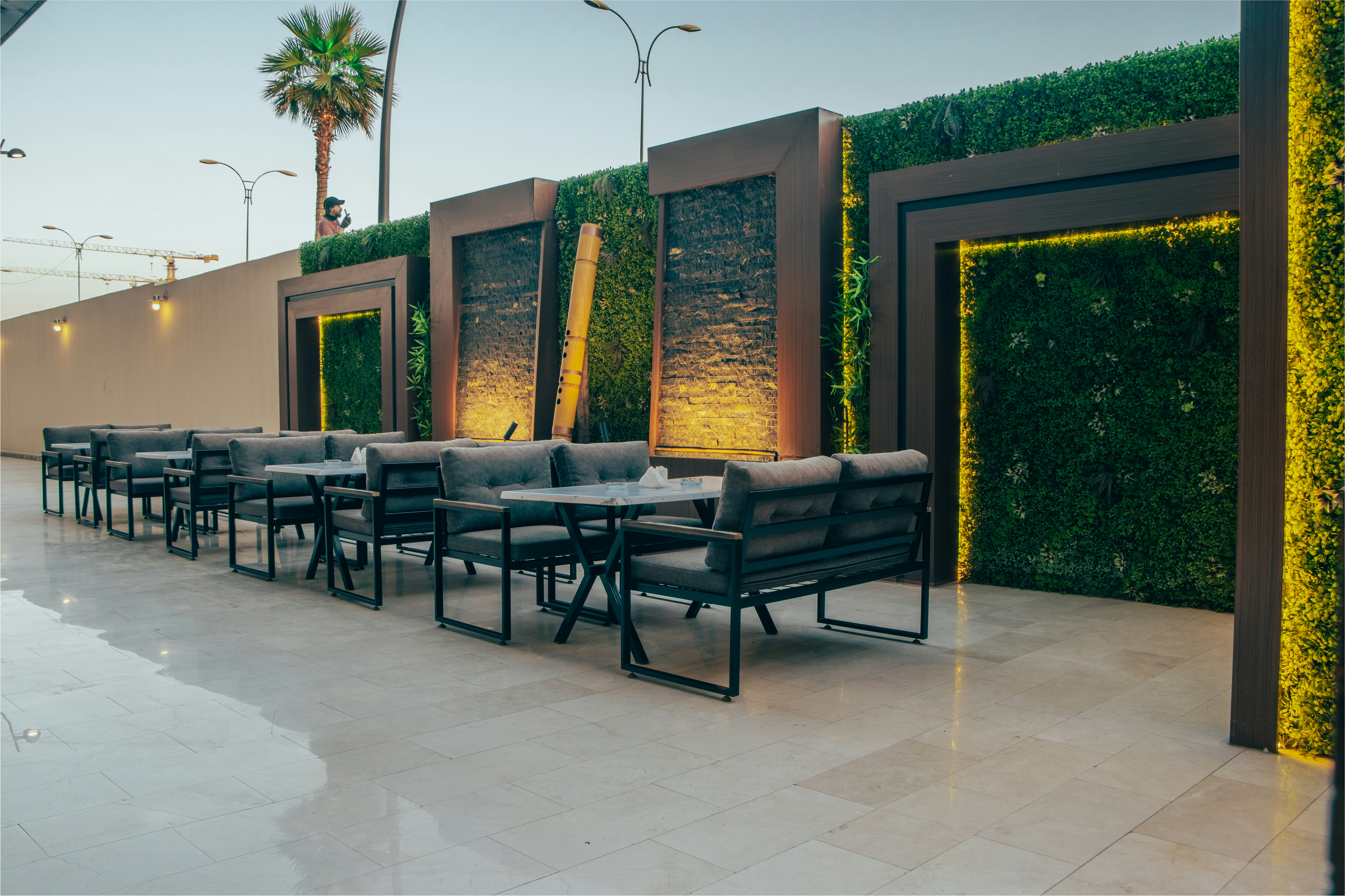 rooftop lounge area with tall planters and privacy screens separating seating zones - apartment sunbathing on rooftop
