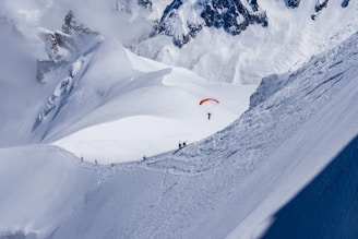 a person paragliding over a snow covered mountain