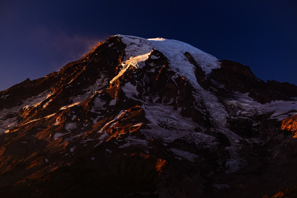 a very tall snow covered mountain under a blue sky