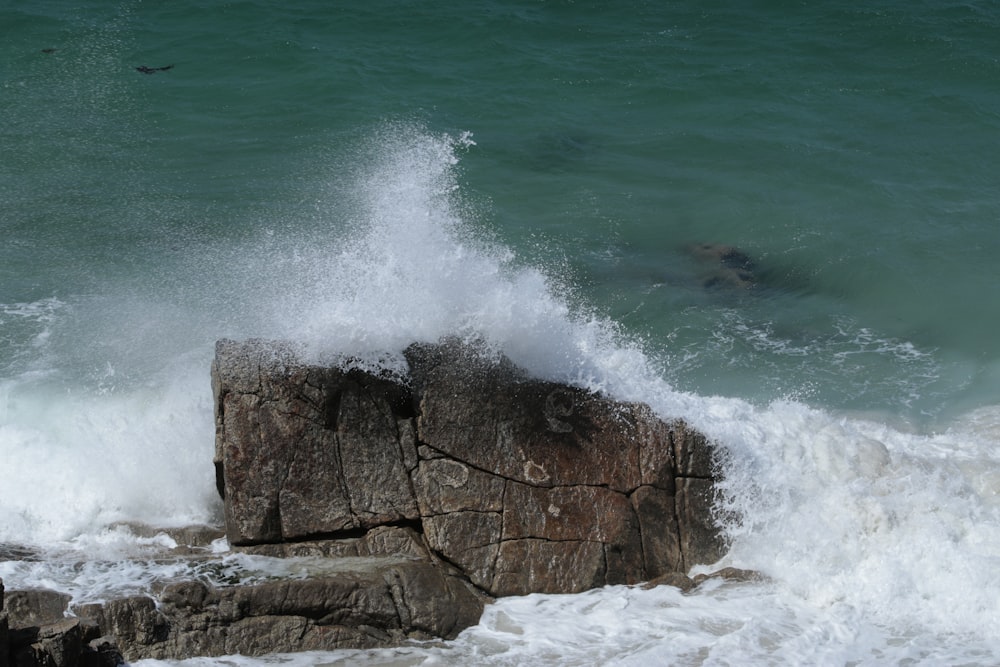 a person swimming in the ocean near a rock