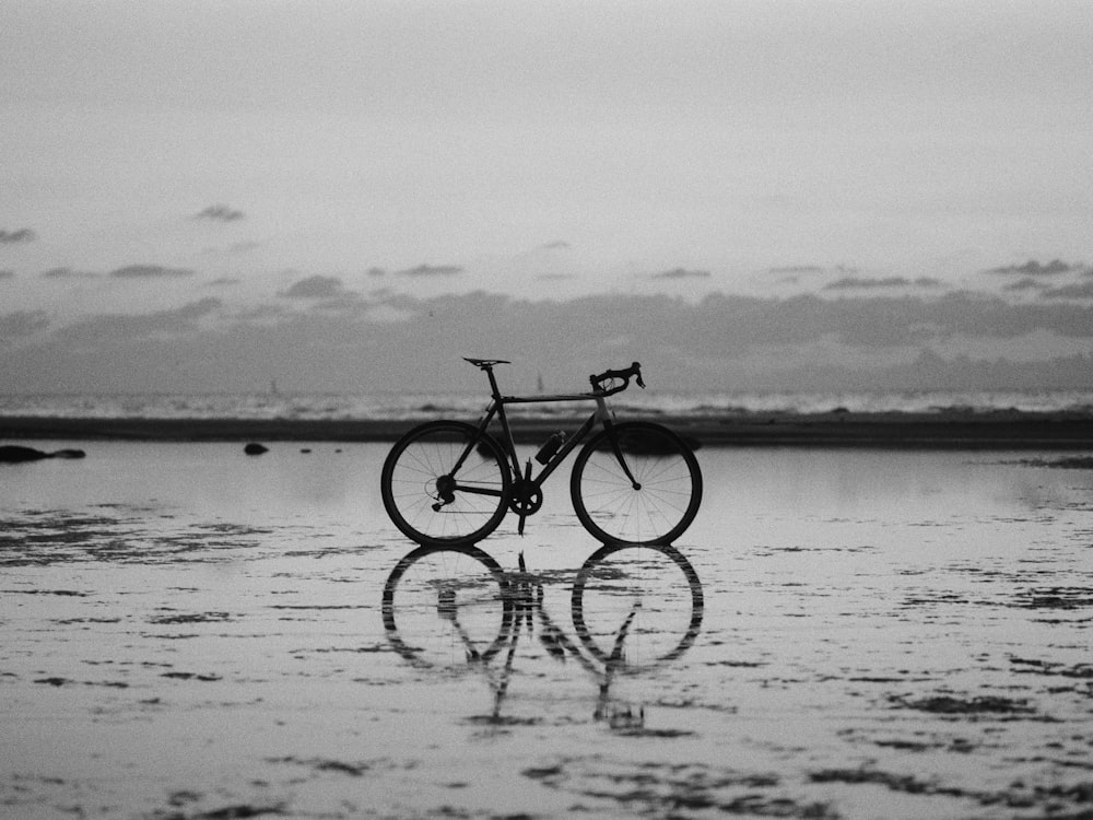 uma foto em preto e branco de uma bicicleta na praia