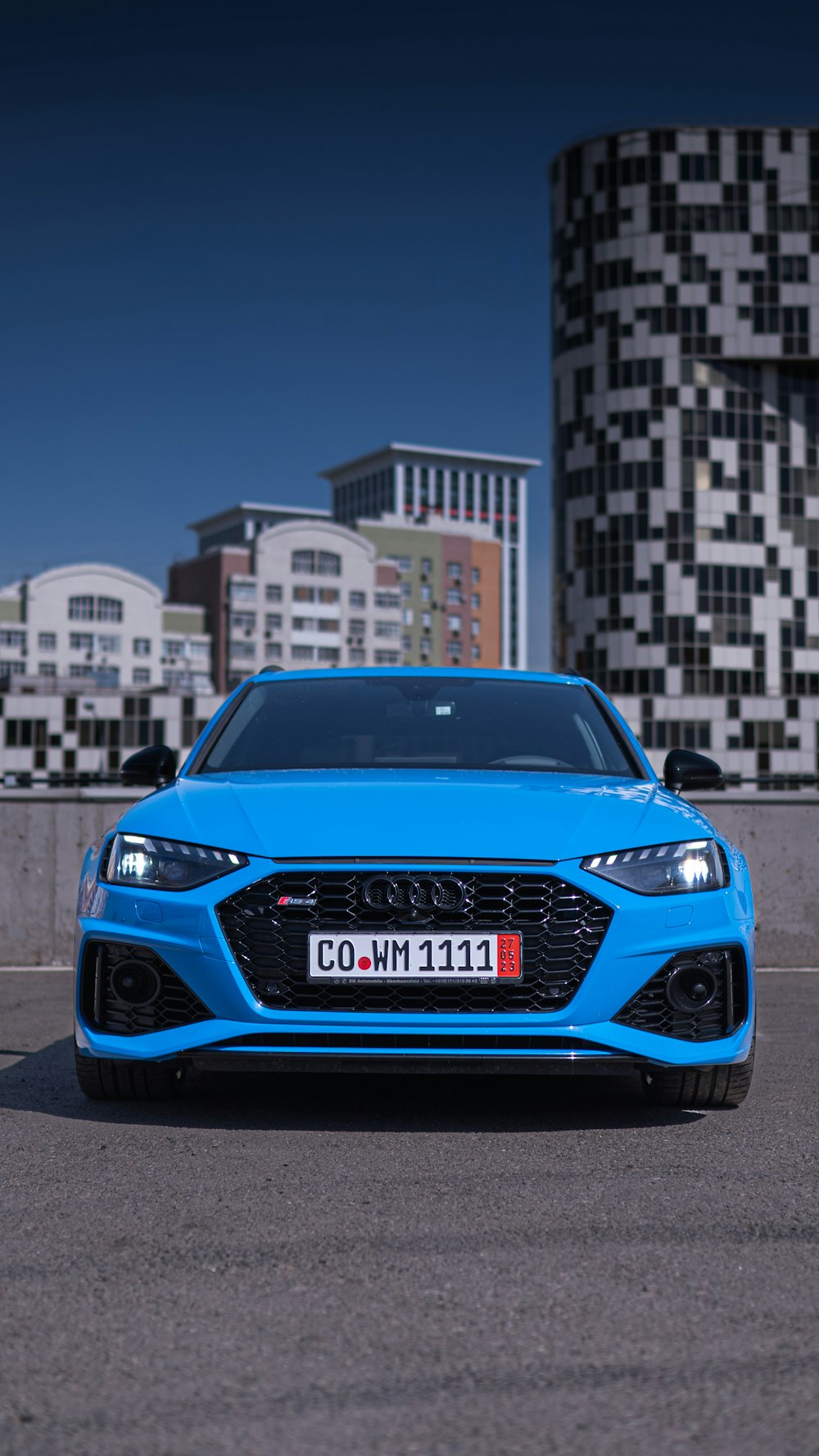 a blue car parked in front of a tall building