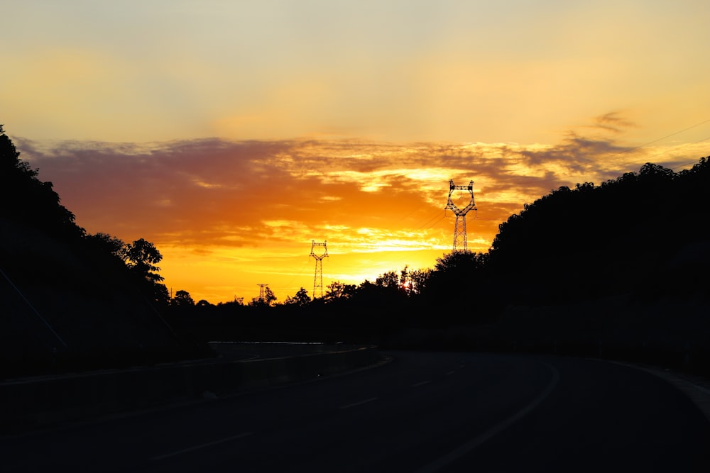 the sun is setting over a rural road