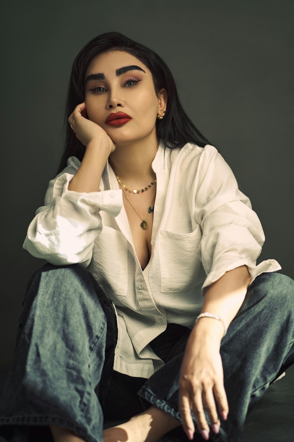 a woman sitting on the ground with her hand on her chin