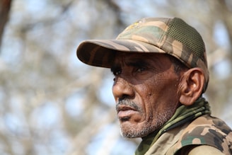 A rugged military veteran wearing a salty by design hoodie, standing confidently with a weathered backdrop.