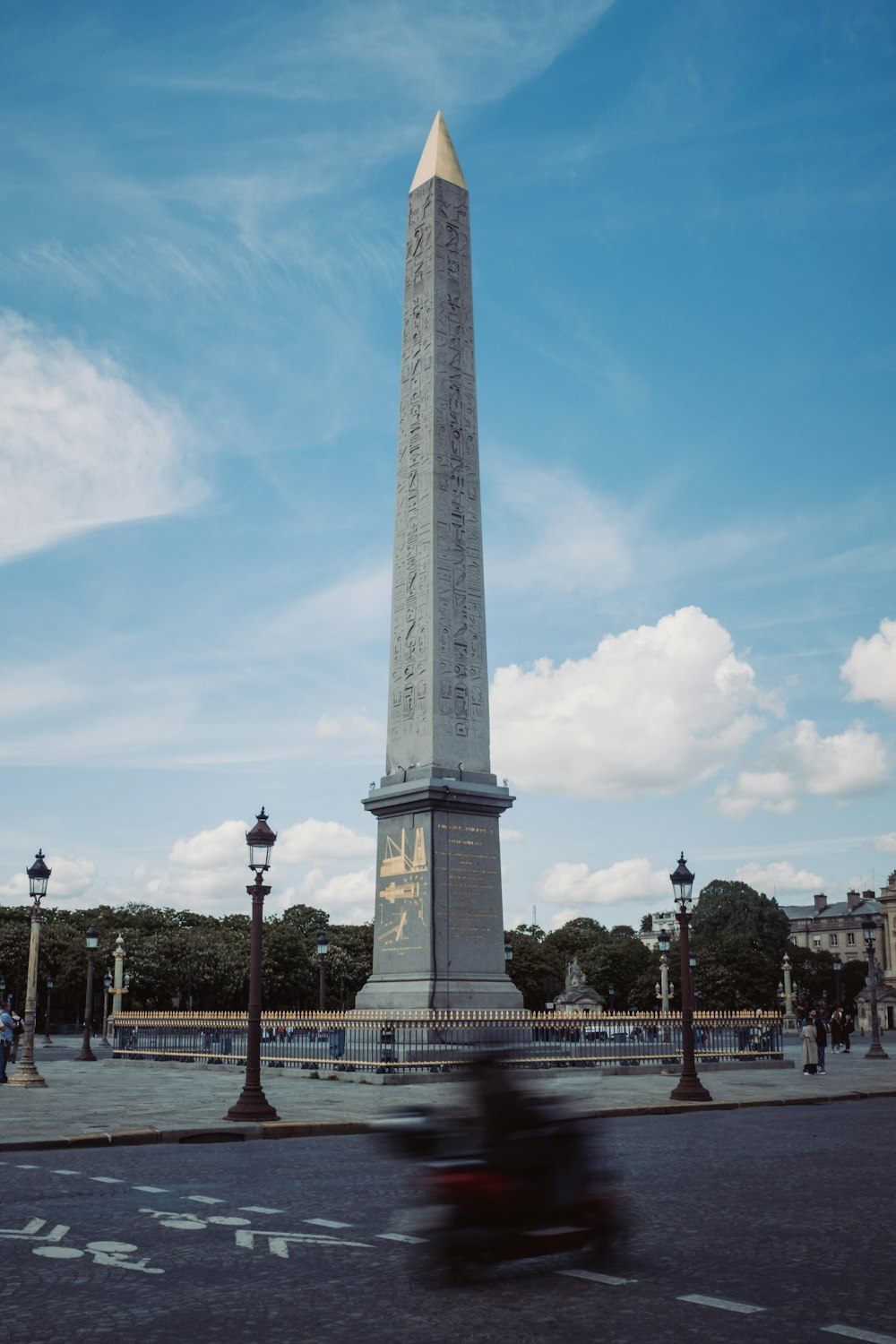 a motorcyclist rides past a monument in a city