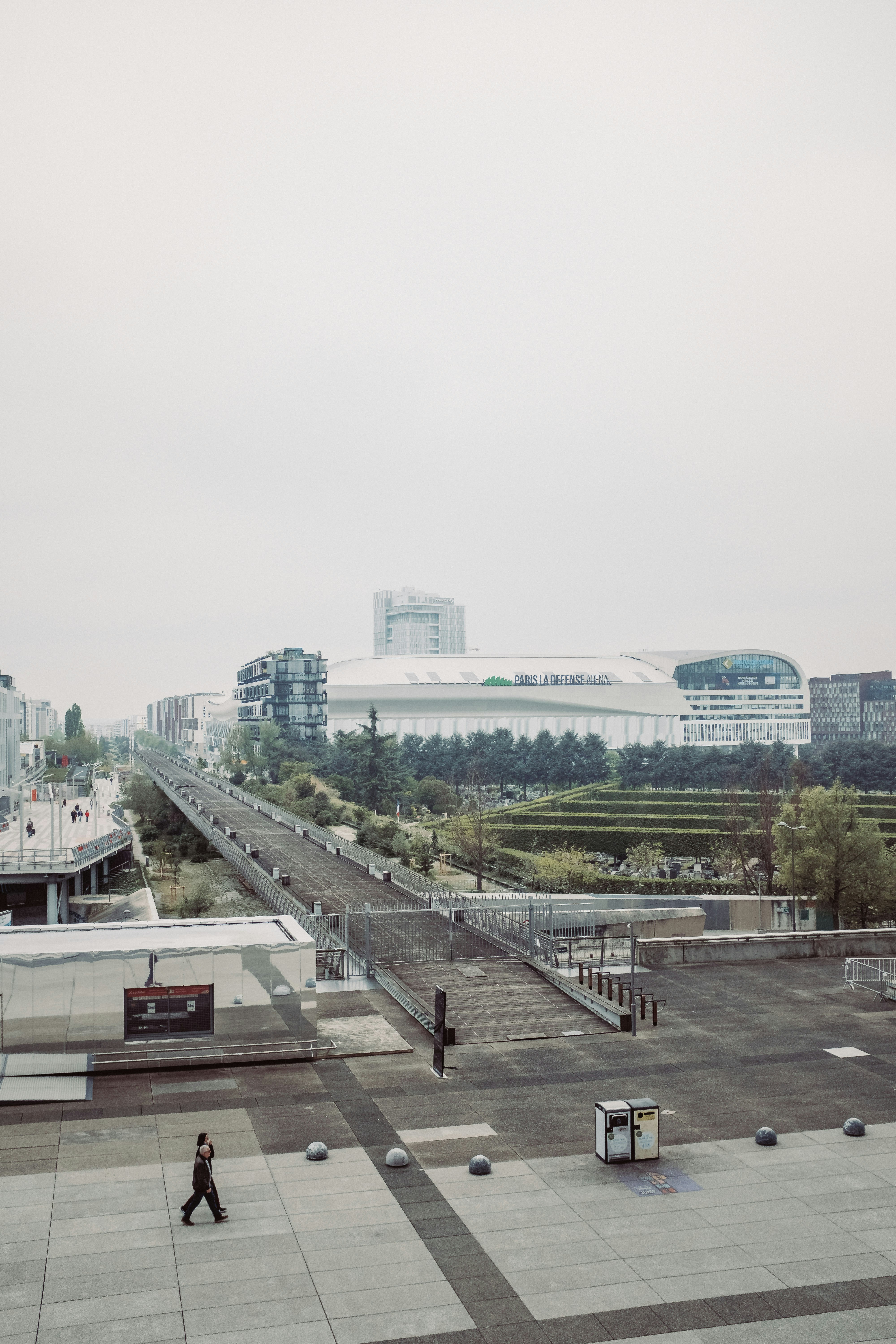 a man walking across a cement walkway next to a parking lot