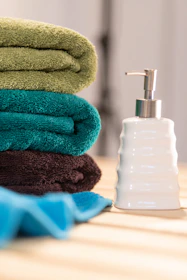 a stack of towels sitting next to a soap dispenser