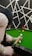 A person is poised to take a shot on a green snooker or pool table. The player, seen from behind, holds a cue stick aimed at several colored balls on the table. The background features a geometric black and white pattern, adding an artistic touch to the scene.