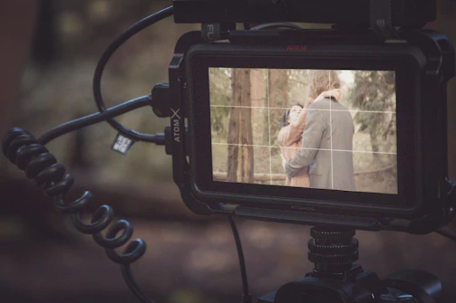 A natural scene showing a couple interacting with a sleek digital prototype, light filtering through trees.