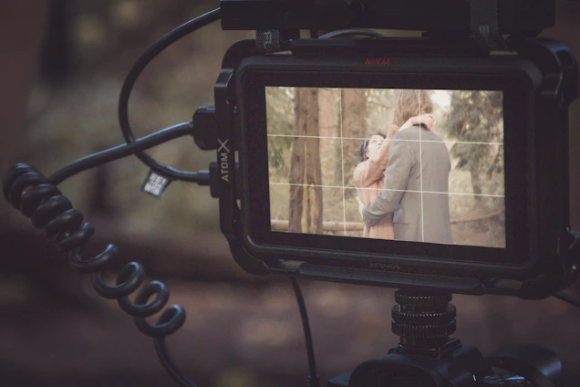 A candid behind-the-scenes shot of a filmmaker capturing an emotional moment between two people outdoors.