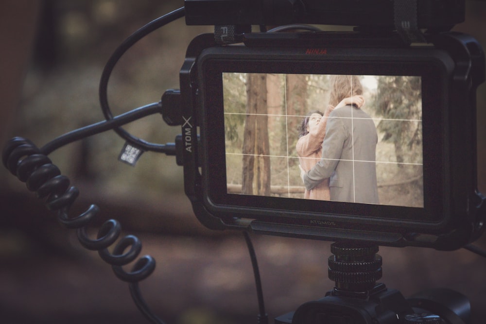 a video camera recording a couple kissing in the woods