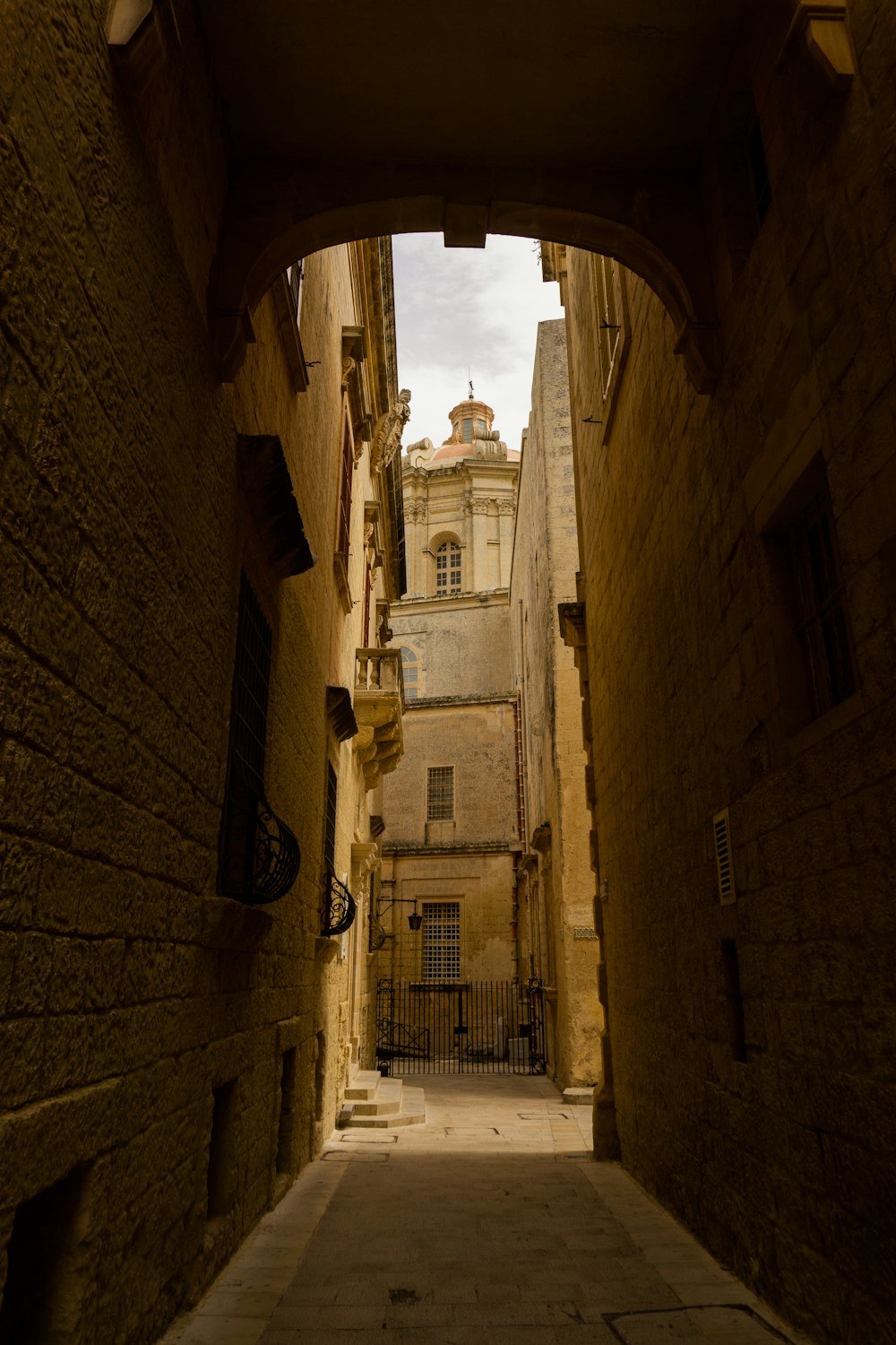 a narrow alley way with a clock tower in the distance