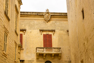 Historic stone building facade in Saint-Malo with traditional wooden shutters.