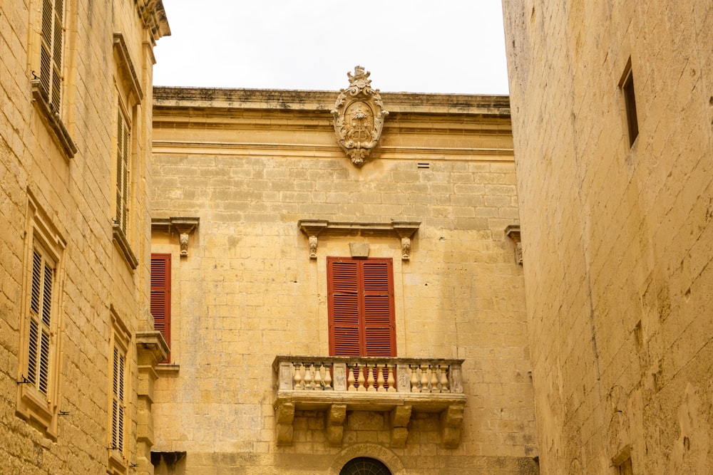 a building with a balcony and red shutters