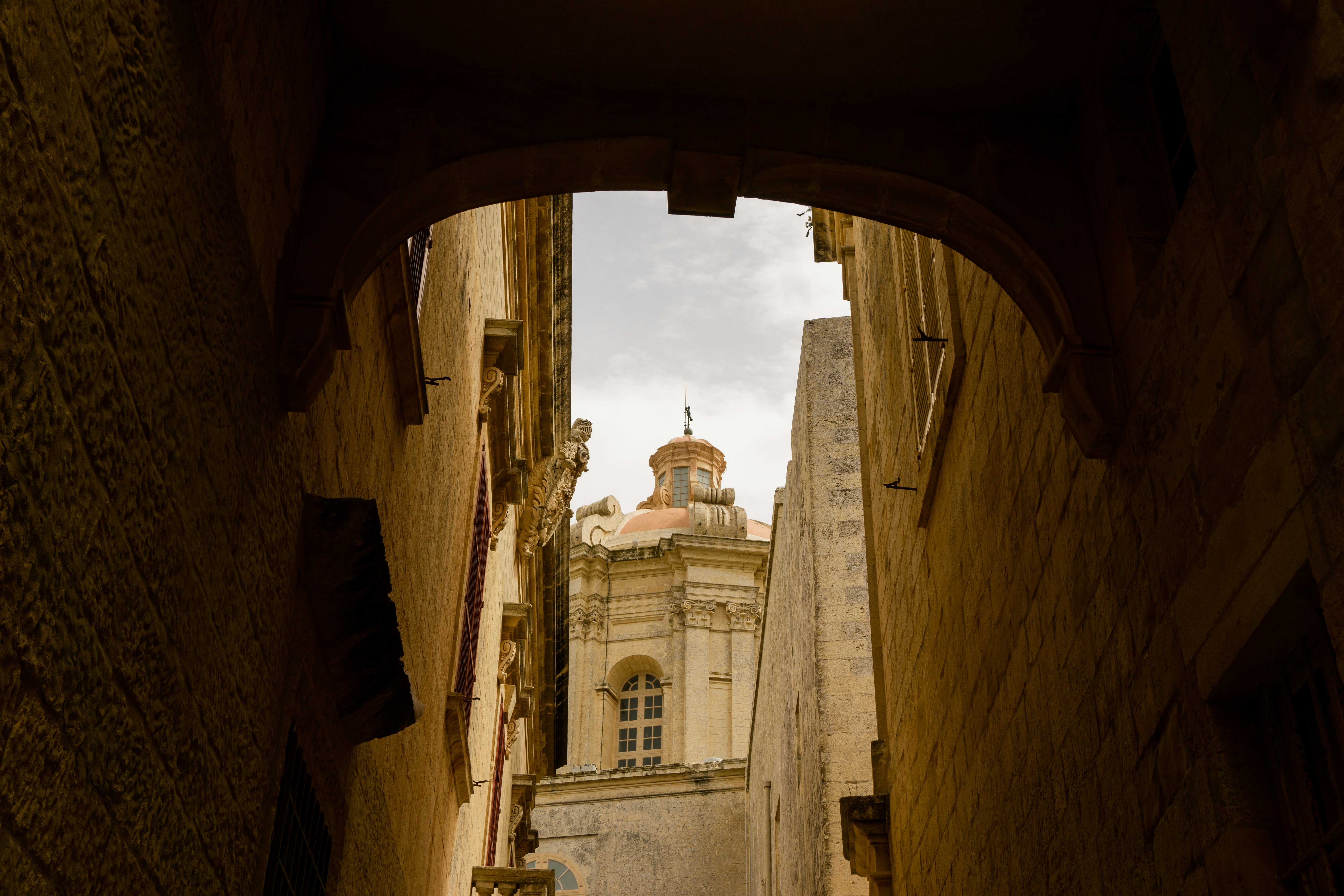 a narrow alley way with a clock tower in the distance