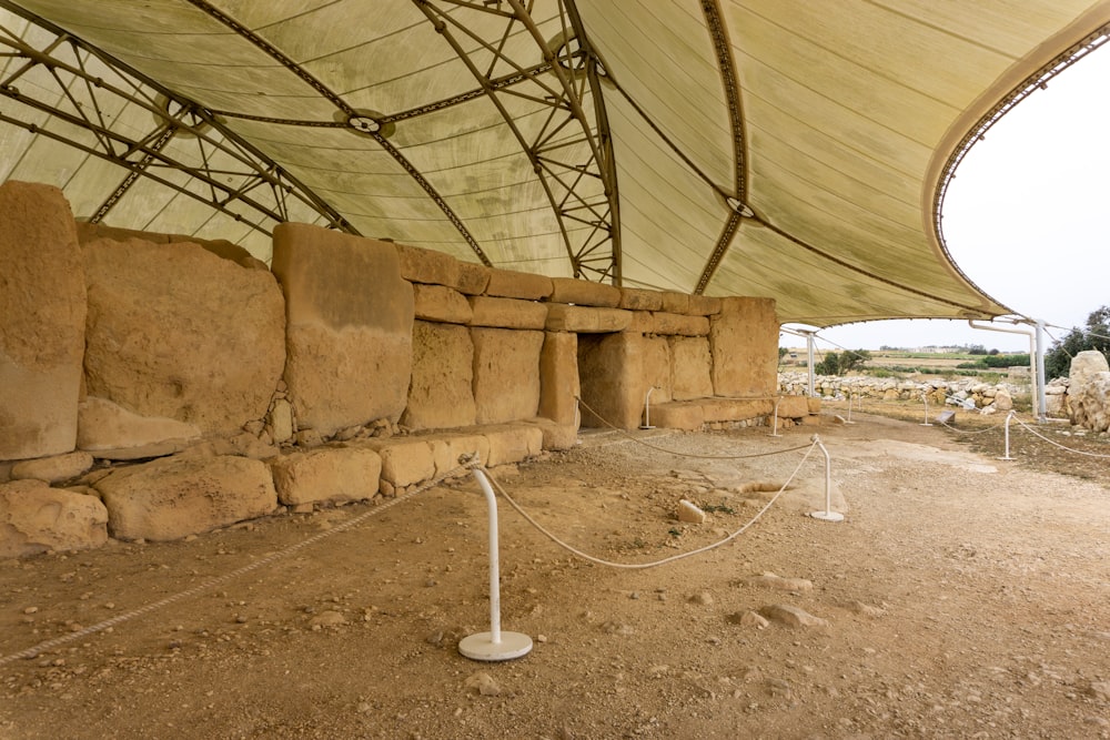 a stone wall under a large tent with ropes