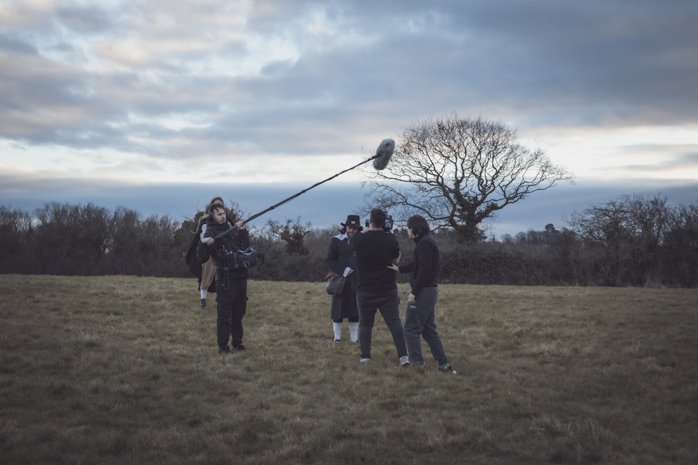 a group of people standing on top of a grass covered field