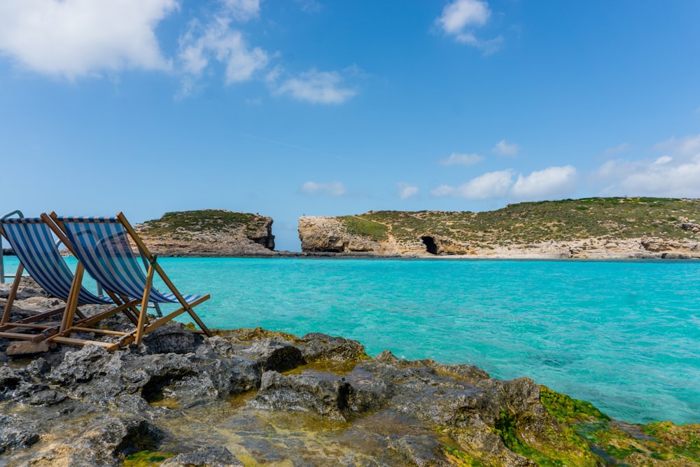 a couple of lawn chairs sitting on top of a rocky beach