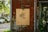 A wooden sign with the text 'FEED FACTORY' and a Chinese character is mounted on a weathered, rust-colored metal wall. The background features parked cars and green trees, creating a blend of urban and natural elements.