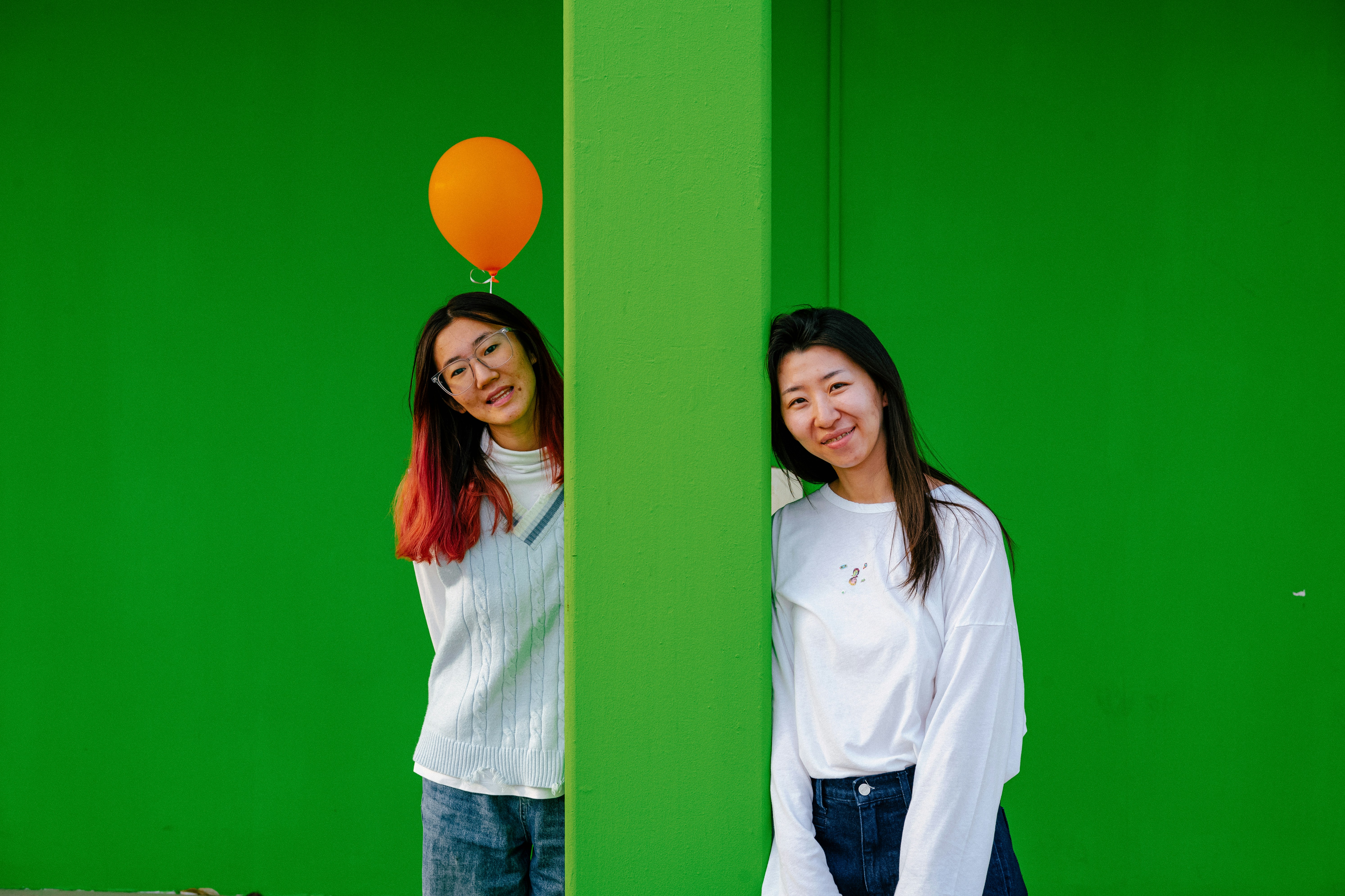 two women standing next to each other with a balloon on their head