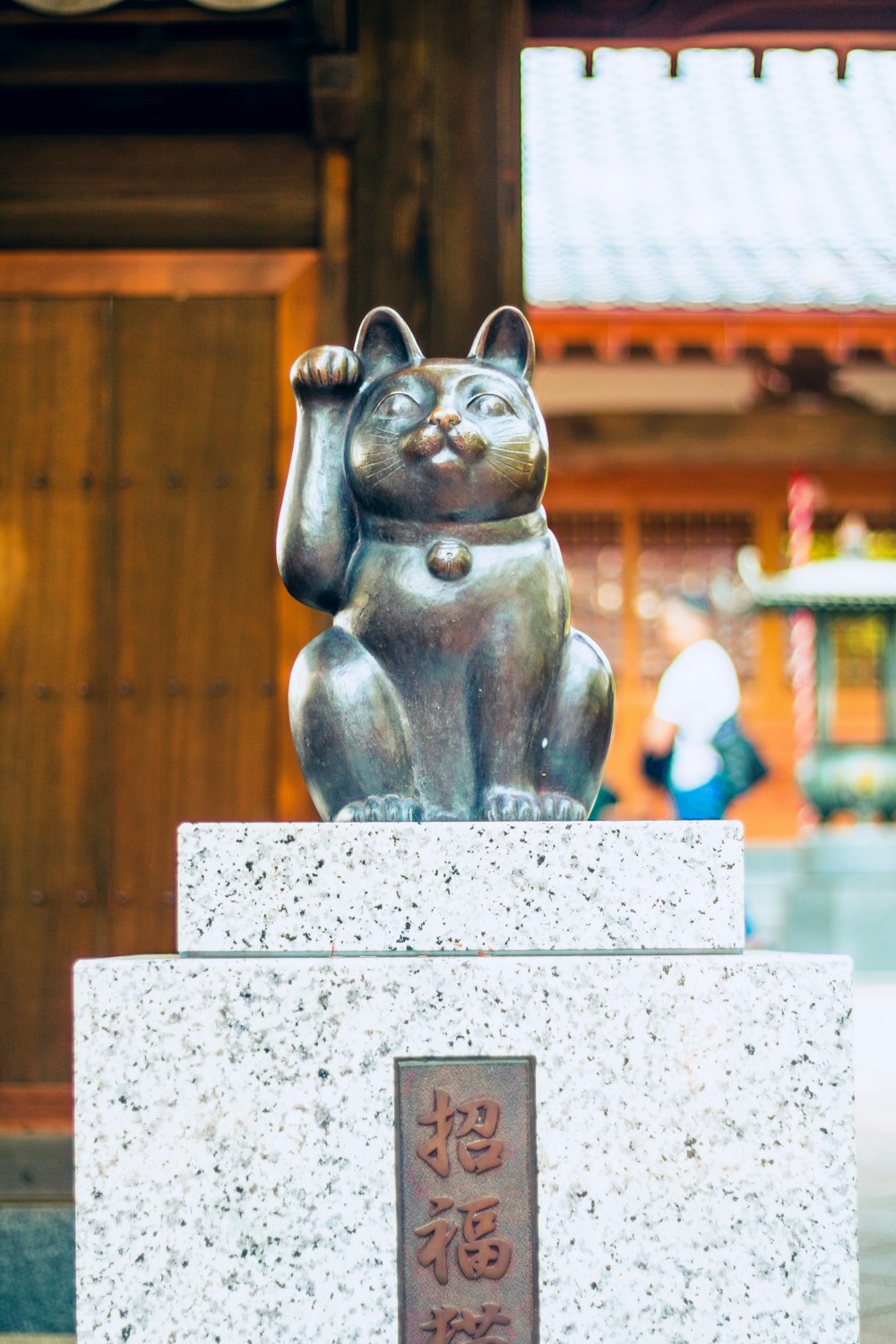 a statue of a cat sitting on top of a stone block