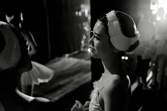 An intimate backstage moment showing actors preparing costumes and makeup under soft lighting.