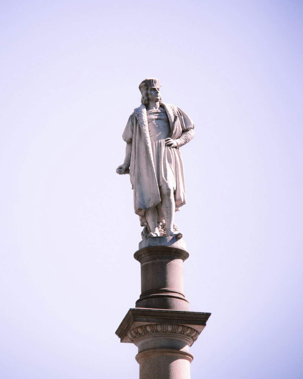 a statue of a man standing on top of a pillar