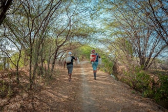 a couple of people walking down a dirt road