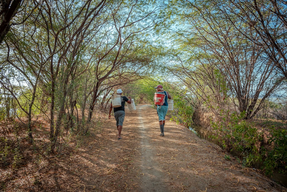 a couple of people walking down a dirt road