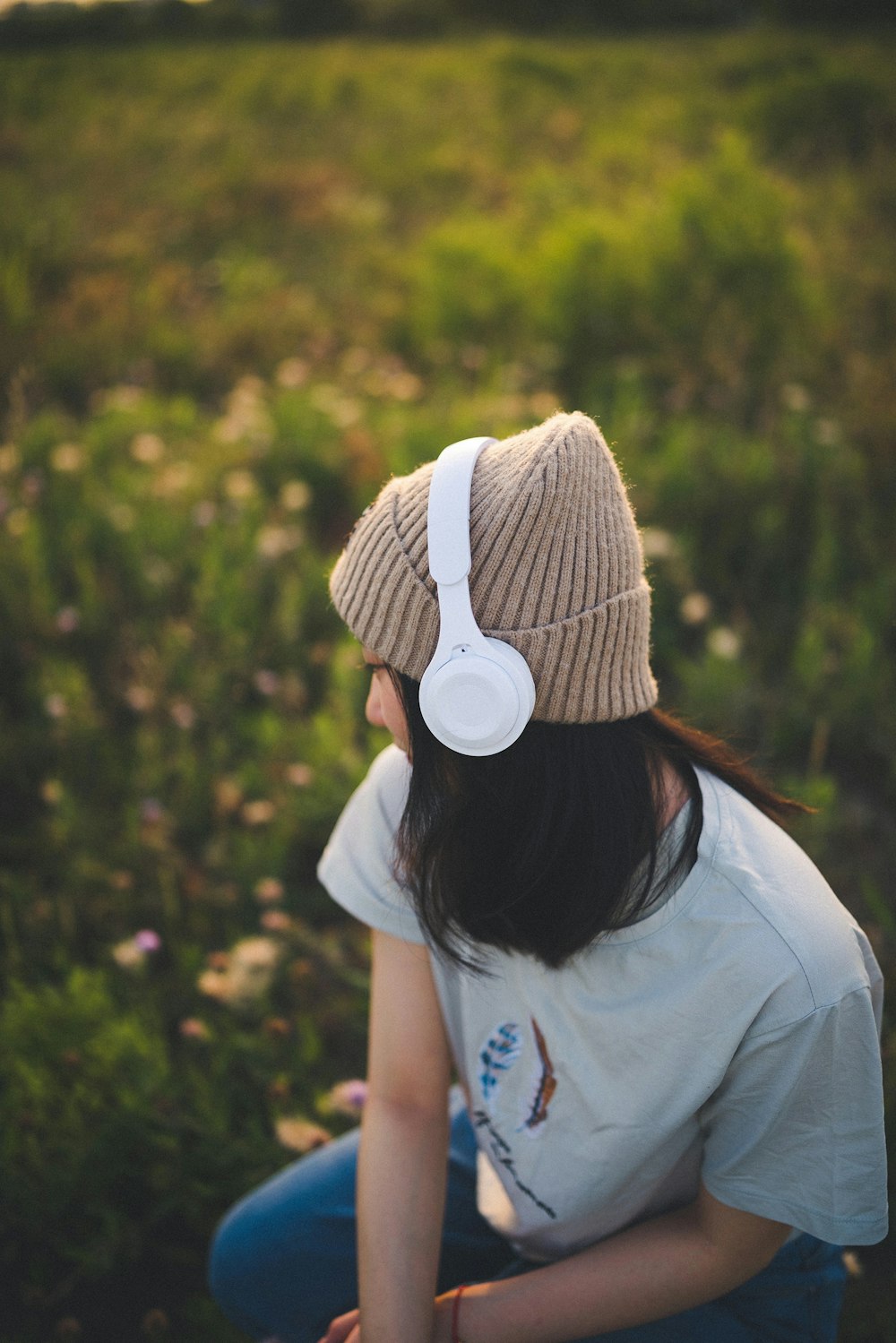a woman sitting in a field with headphones on