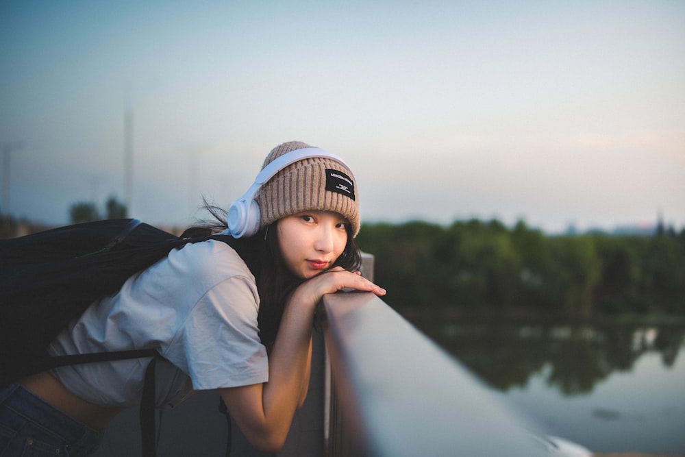 a woman leaning on a rail with a backpack on her shoulder