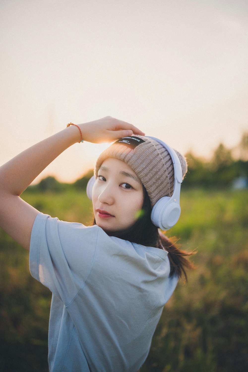 a woman wearing headphones standing in a field