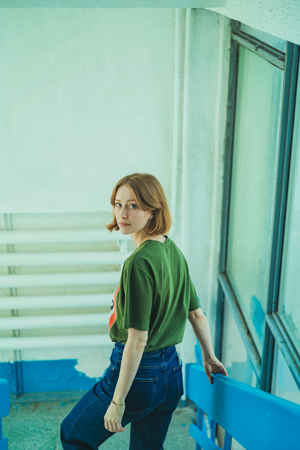 a woman in a green shirt leaning against a blue rail