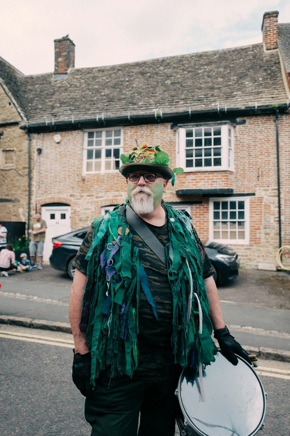 a man with a beard and a green hat holding a drum