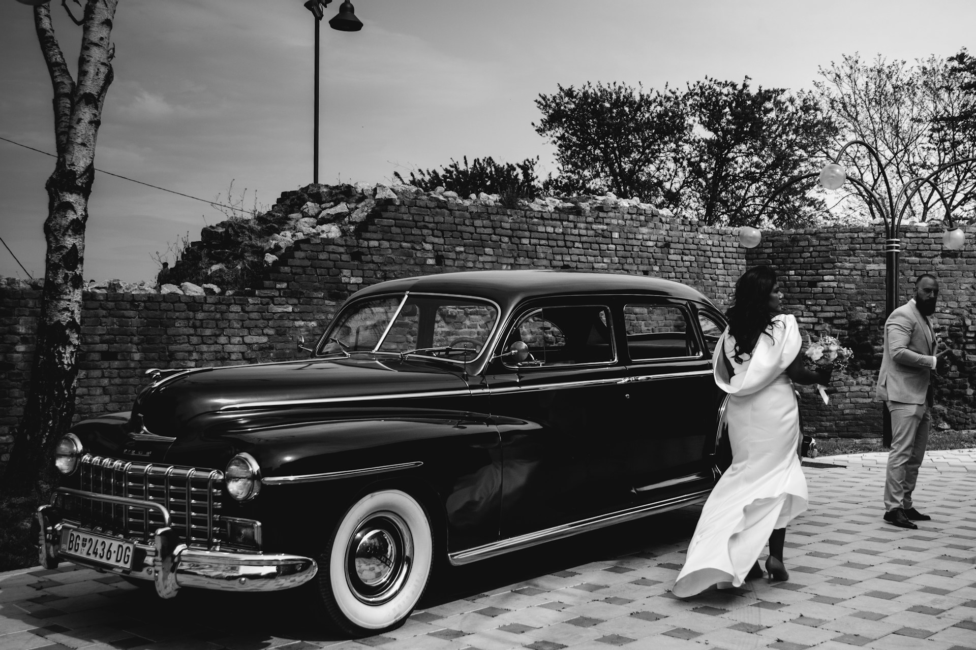 a man and woman walking next to an old car