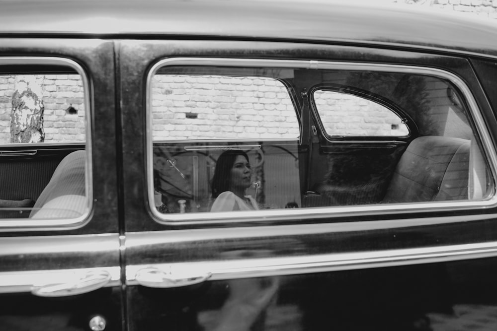a black and white photo of a woman in a car