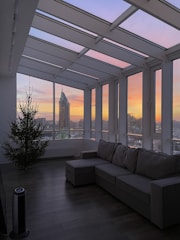 A spacious living area with modern furniture and a view of the sunset.