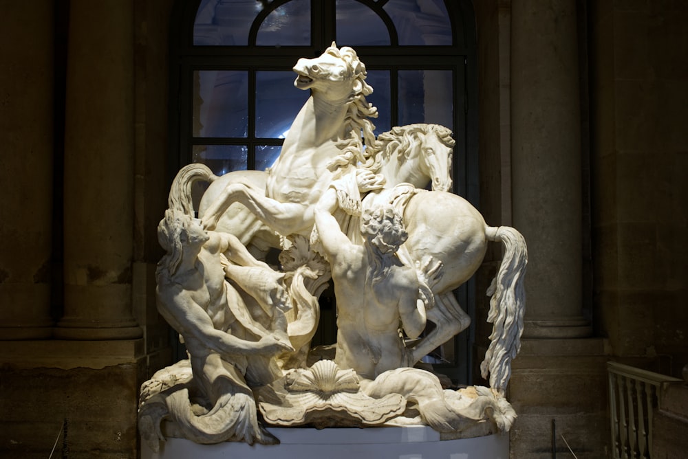 a statue of a group of horses in front of a window