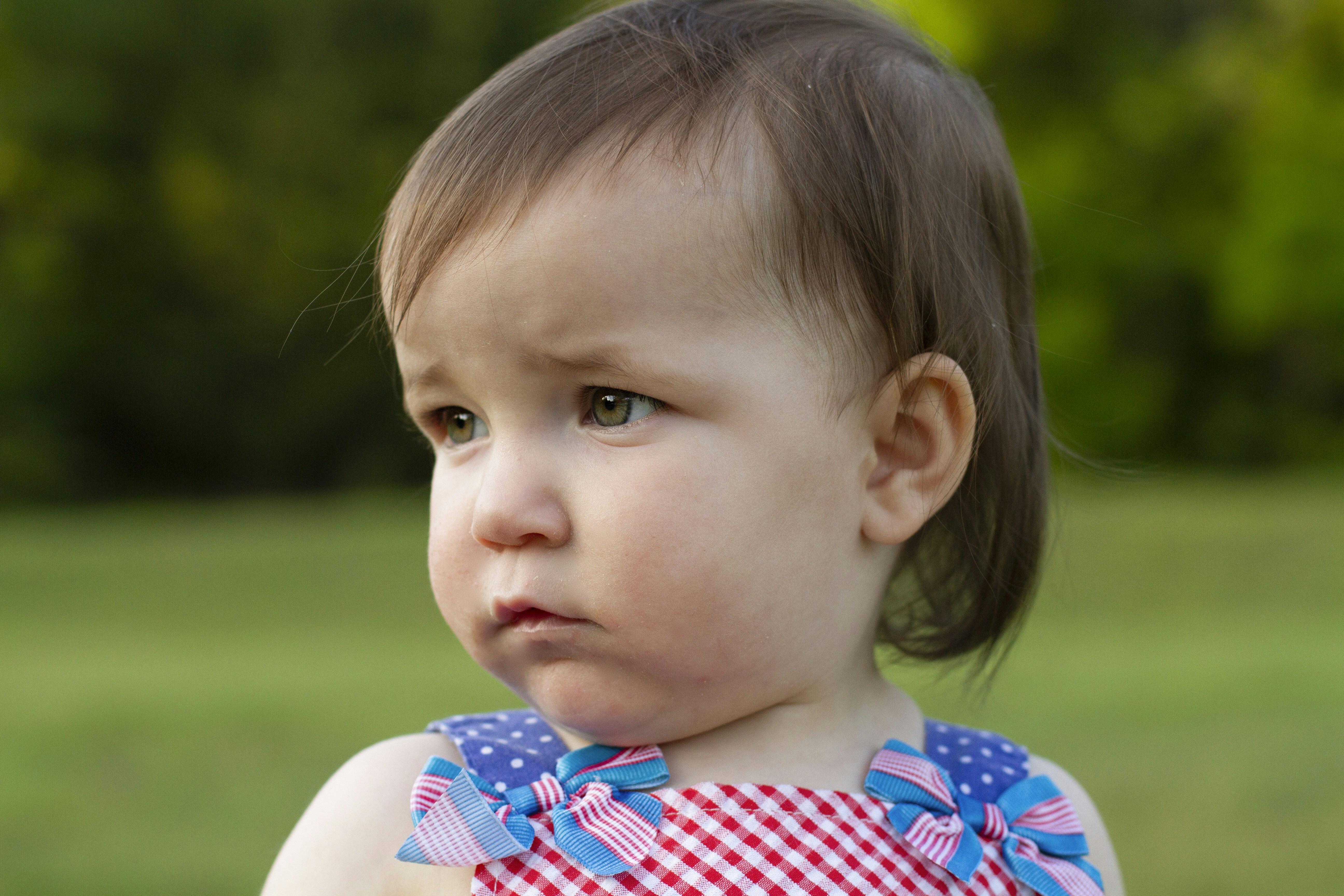 a little girl in a red and blue dress looking at the camera