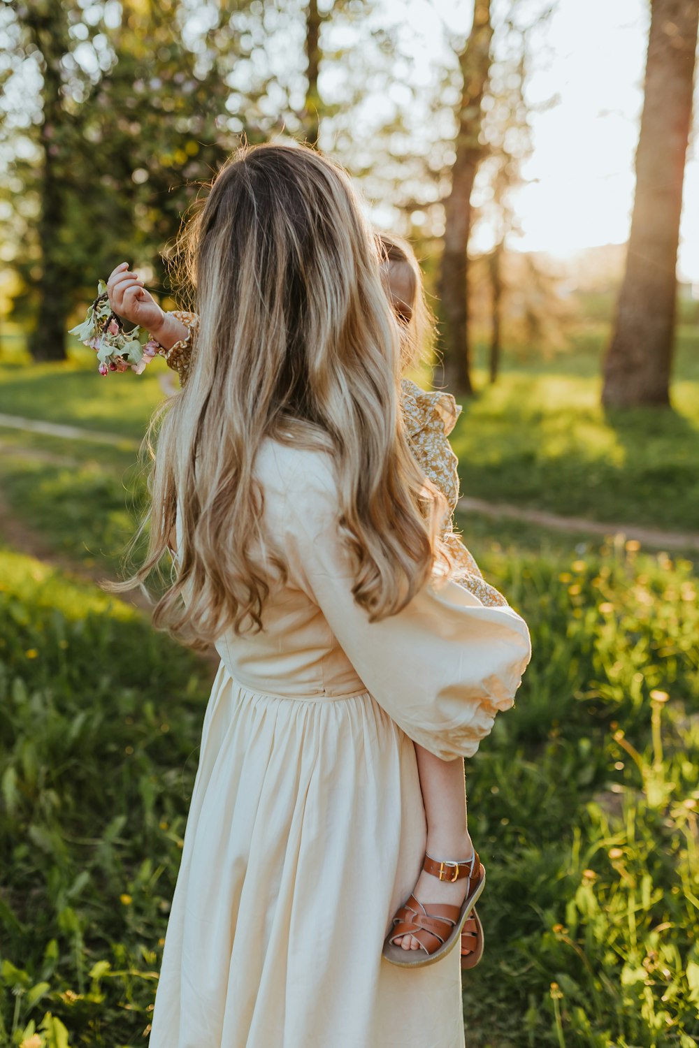 a little girl in a white dress holding a flower