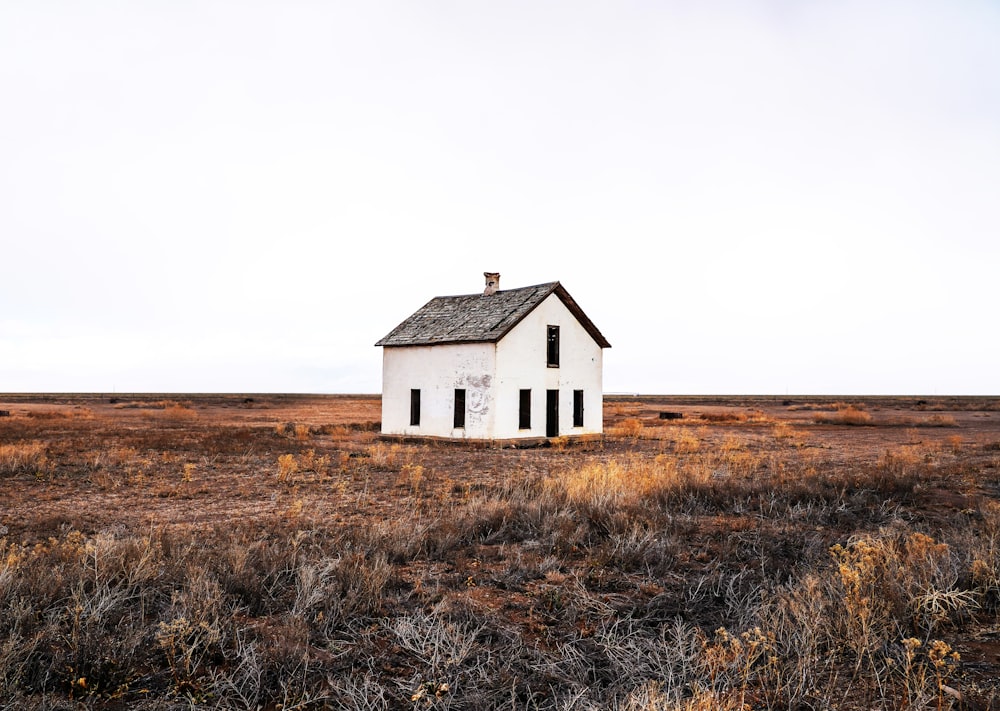 a small white house in a field with a sky background