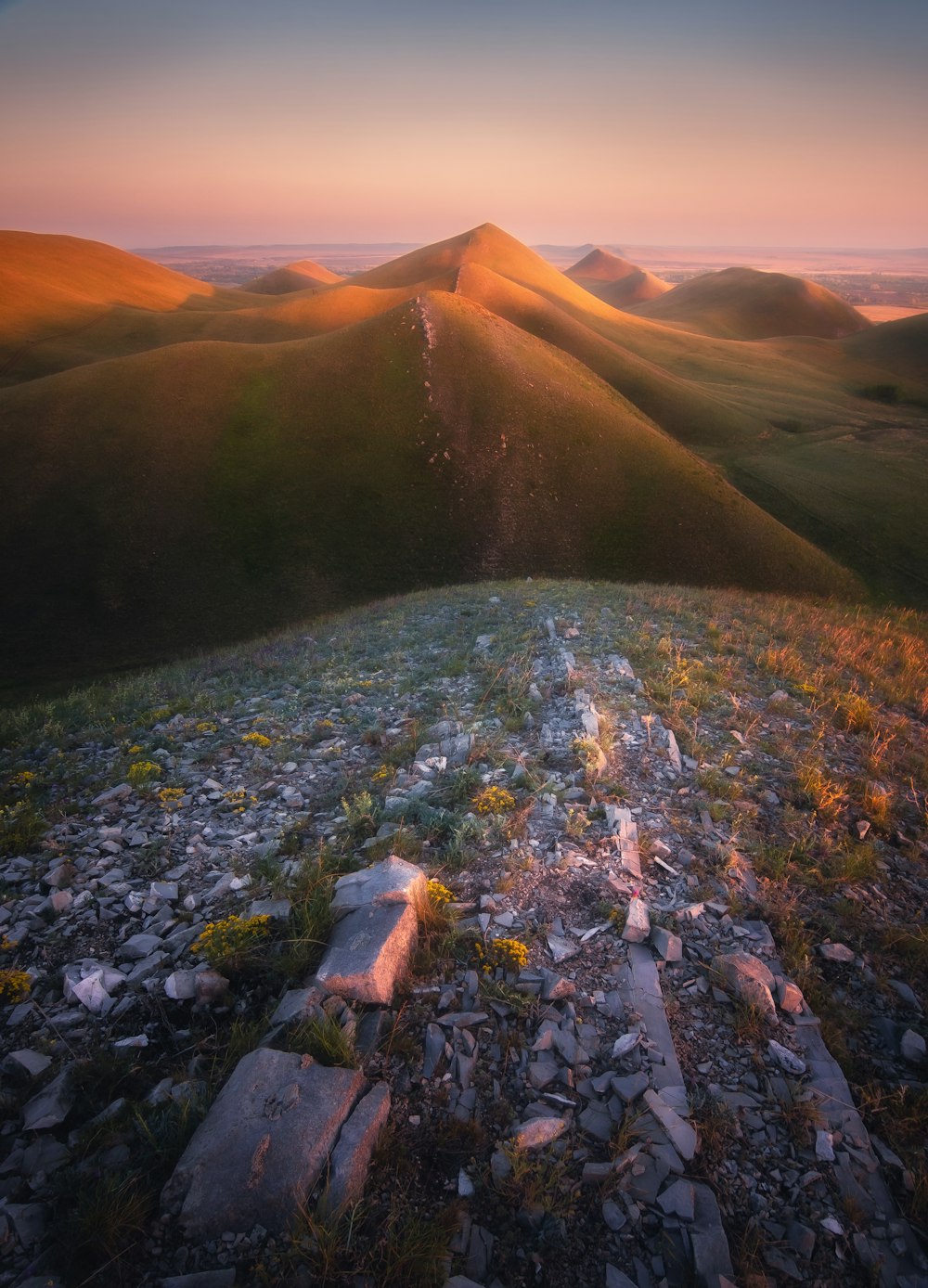 the sun is setting over the hills and rocks