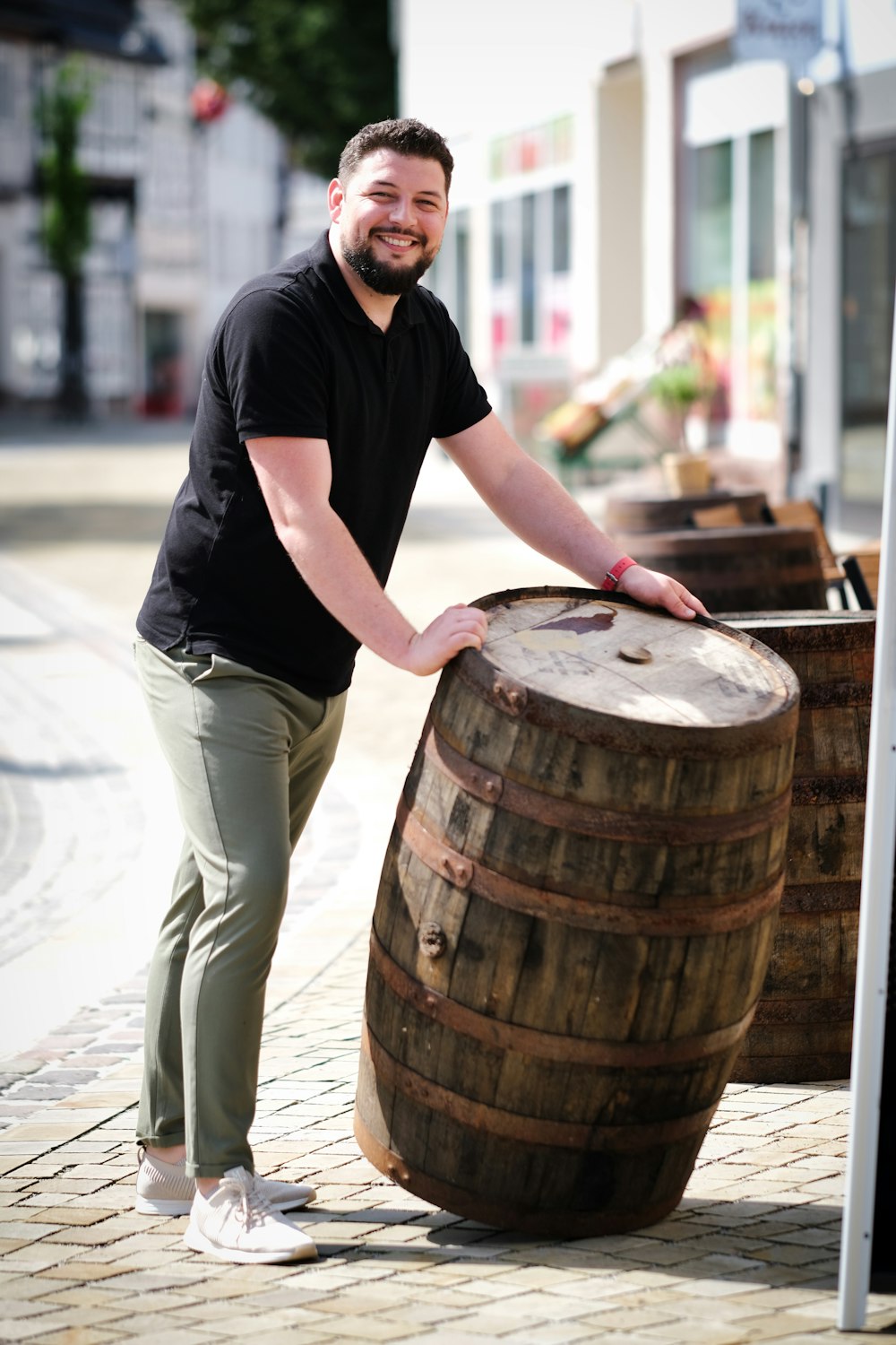 a man standing next to a large wooden barrel