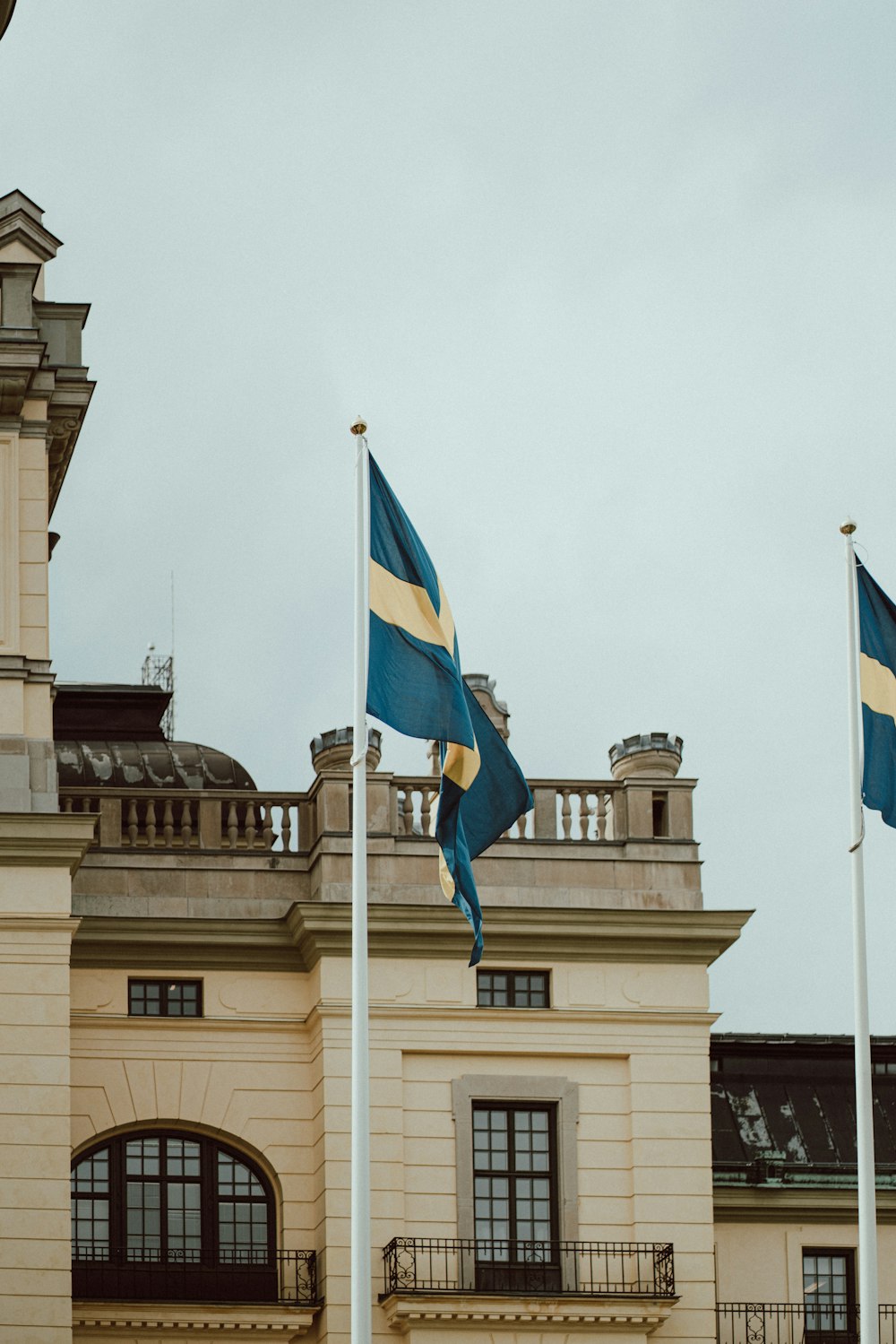 two flags are flying in front of a building