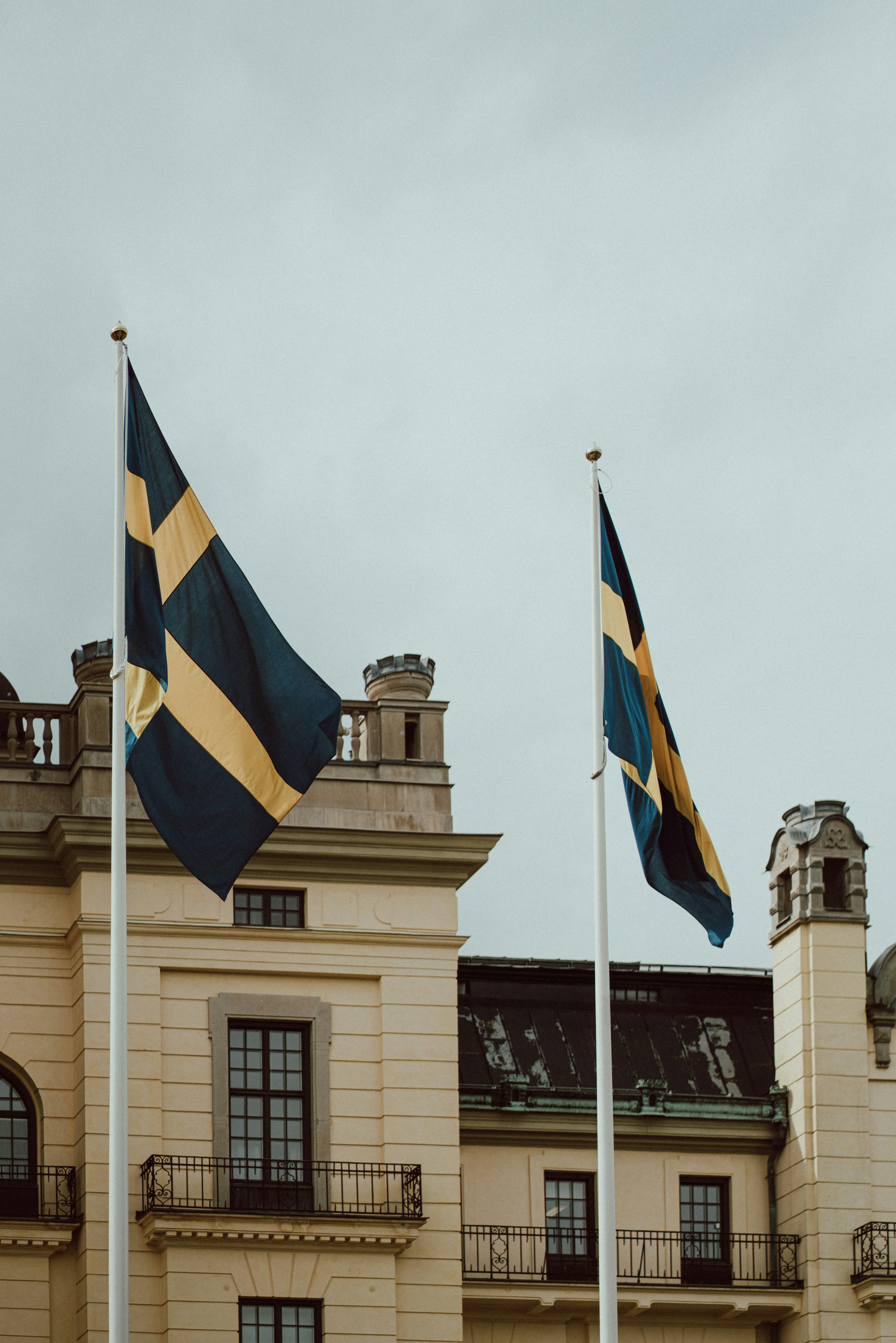 two flags are flying in front of a building